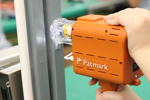 Image of a person holding and using Patmark-mini for engraving